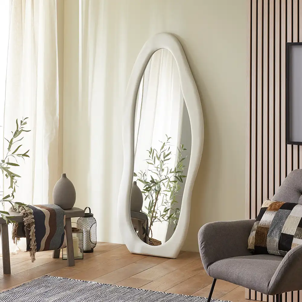 A sculptural full-length mirror with a soft white flannel frame and organic wavy silhouette.