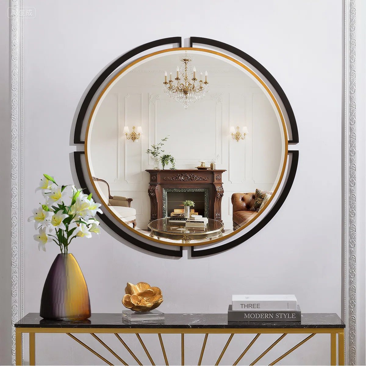 Round wall mirror with black and gold frame reflecting a classic living room with chandelier, fireplace, and leather armchair; white lilies in a vase placed in front.