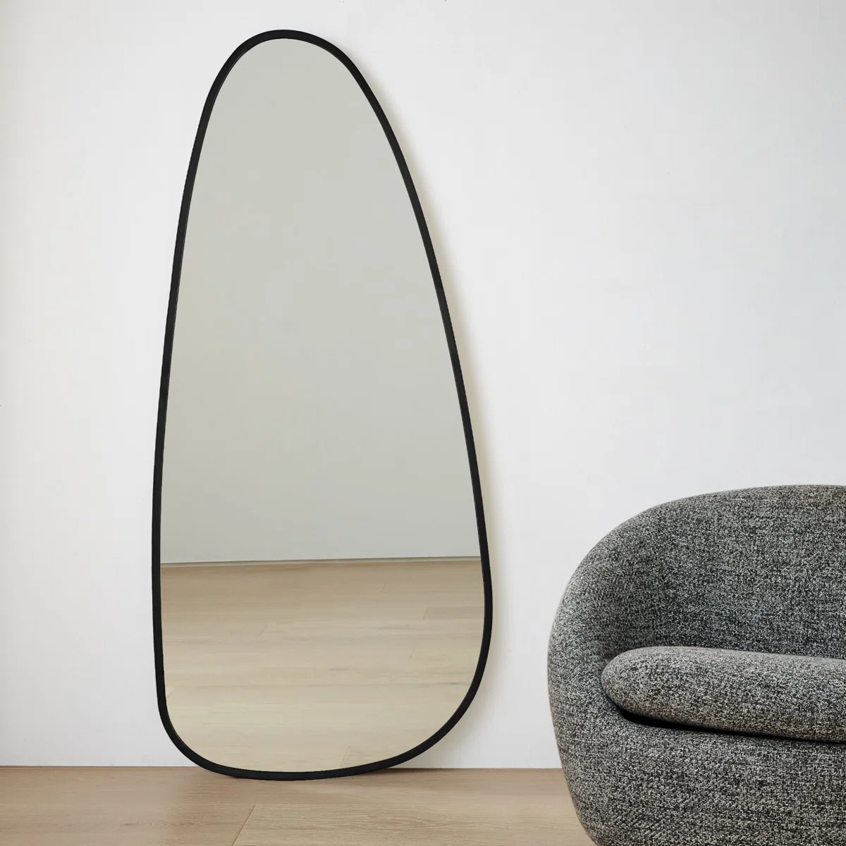 Irregularly shaped wall mirror with a black metal frame, tapering toward the top, mounted against a white background—ideal for modern and minimalist interiors.