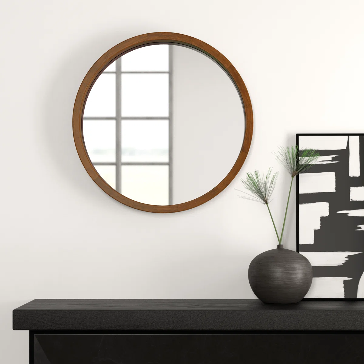 Round wall mirror with rustic wood frame reflecting a sunlit window, placed beside a green decorative plant.