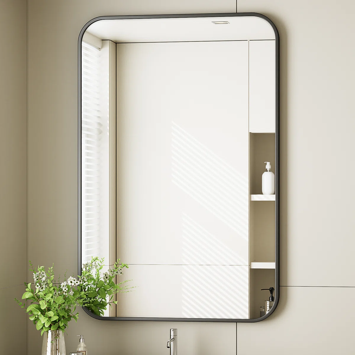 Rectangular wall mirror with a thin black aluminum frame mounted on a dark tiled wall, reflecting a white interior with a tall vase and decorative branches.