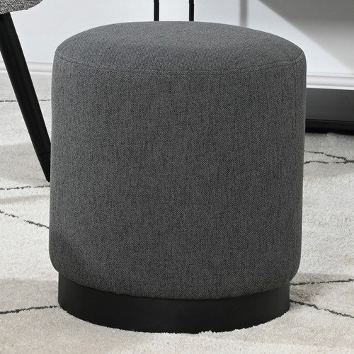 Round upholstered ottoman in dark grey wool-blend fabric with a black metal base, placed on a light patterned rug.