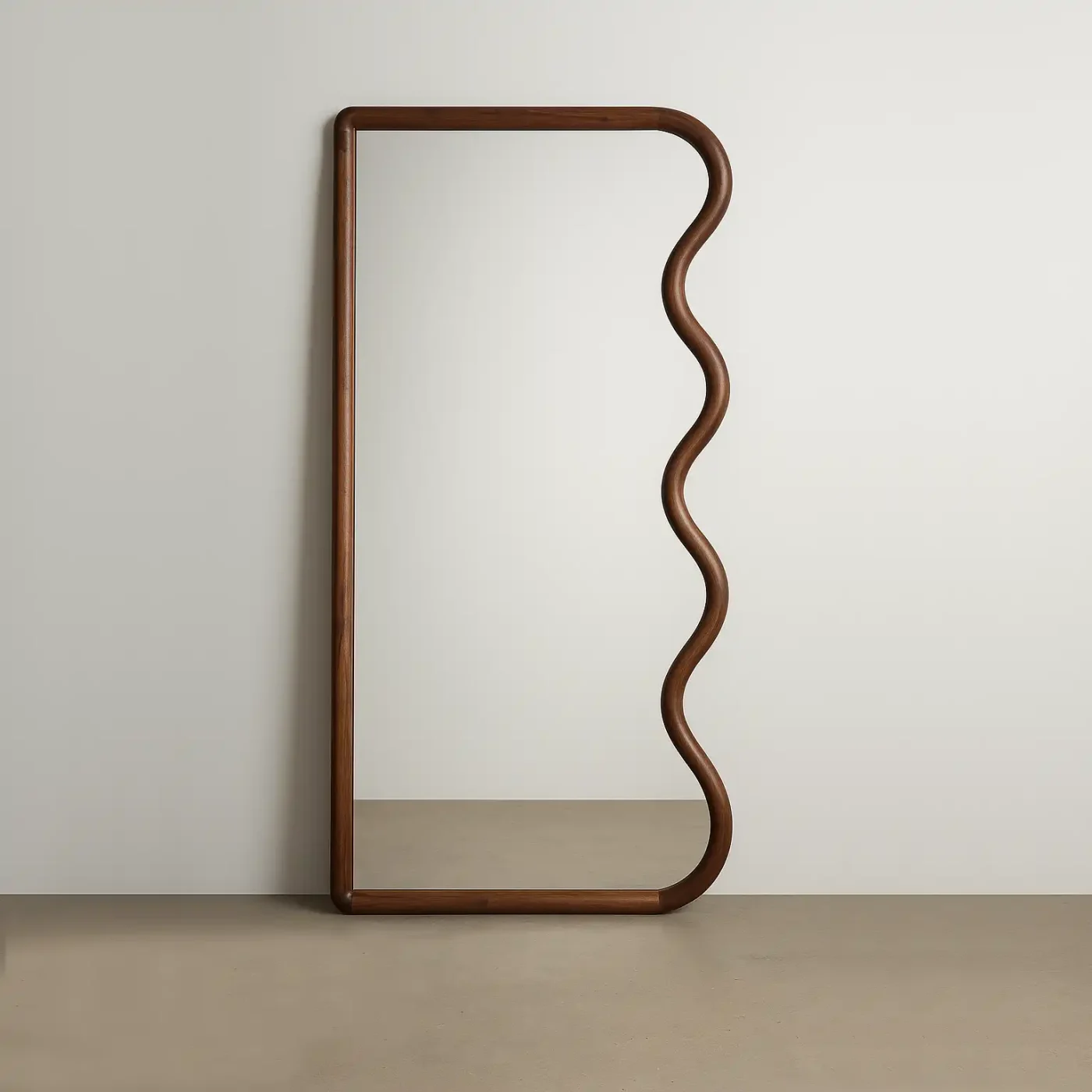 Full-length mirror with a wooden frame featuring a wavy right edge, leaning against a white wall on a neutral floor.