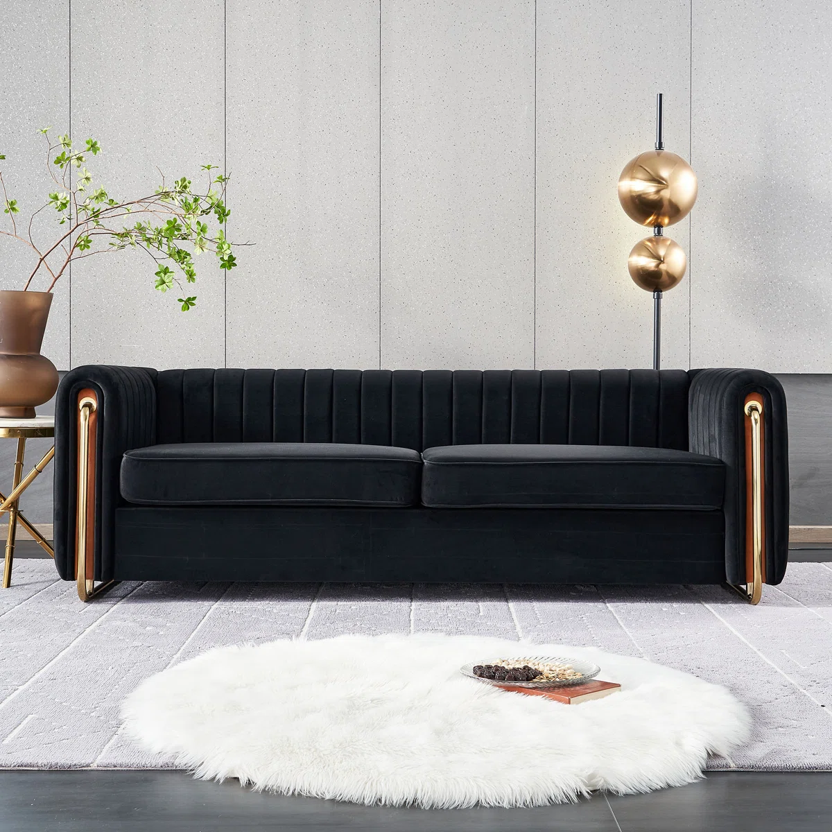 Black velvet sofa with vertical tufting and gold metal legs in a stylish living room with gray rug