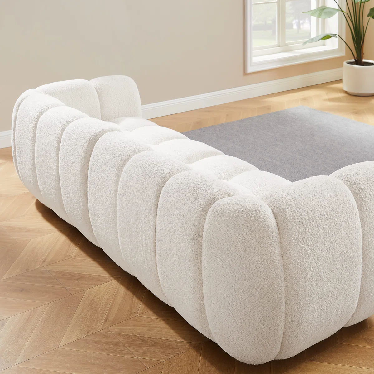 White tufted boucle sofa with rolled arms and throw pillows in a modern living room setting.