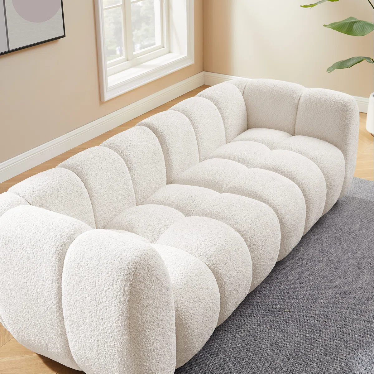 White tufted boucle sofa with rolled arms and throw pillows in a modern living room setting.