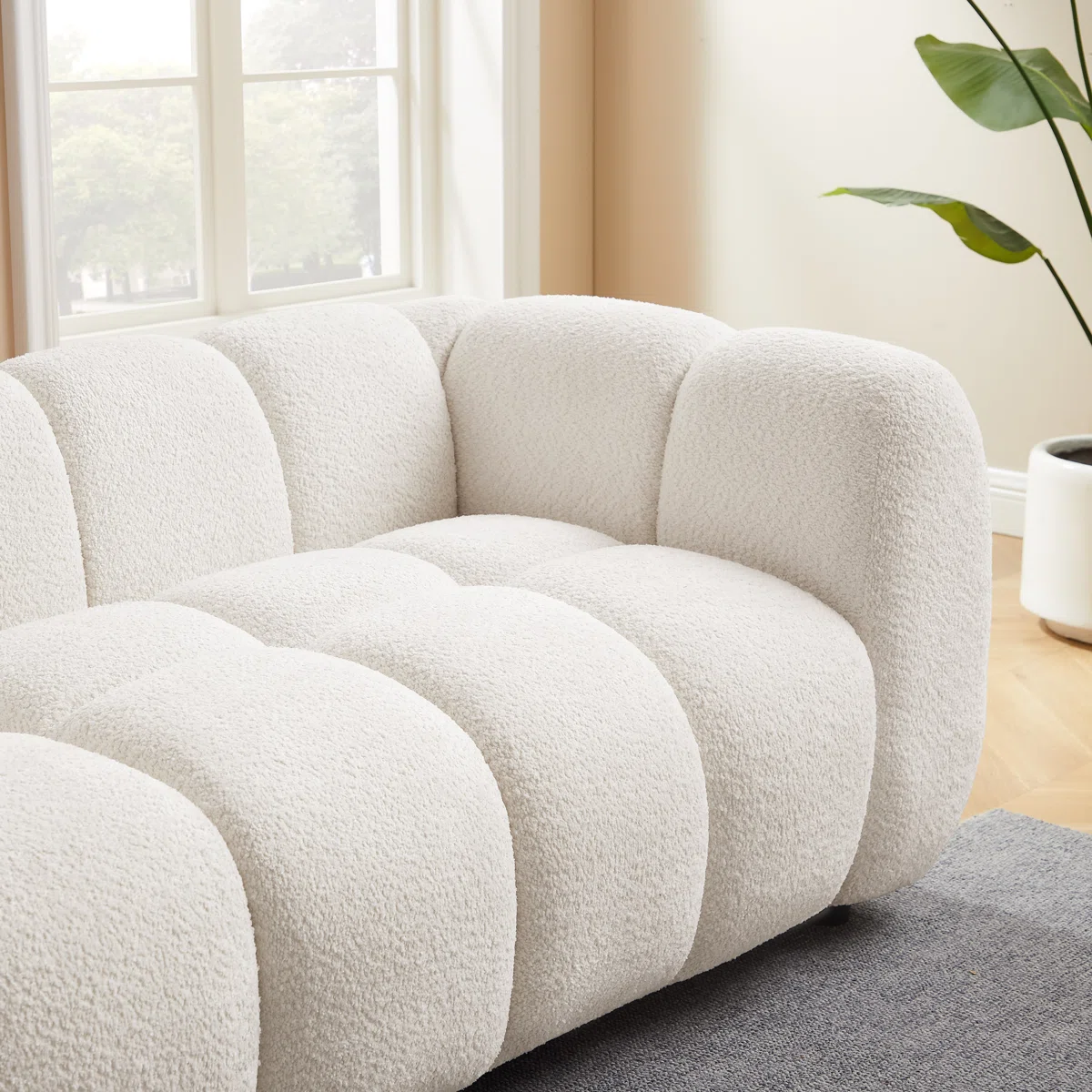 White tufted boucle sofa with rolled arms and throw pillows in a modern living room setting.