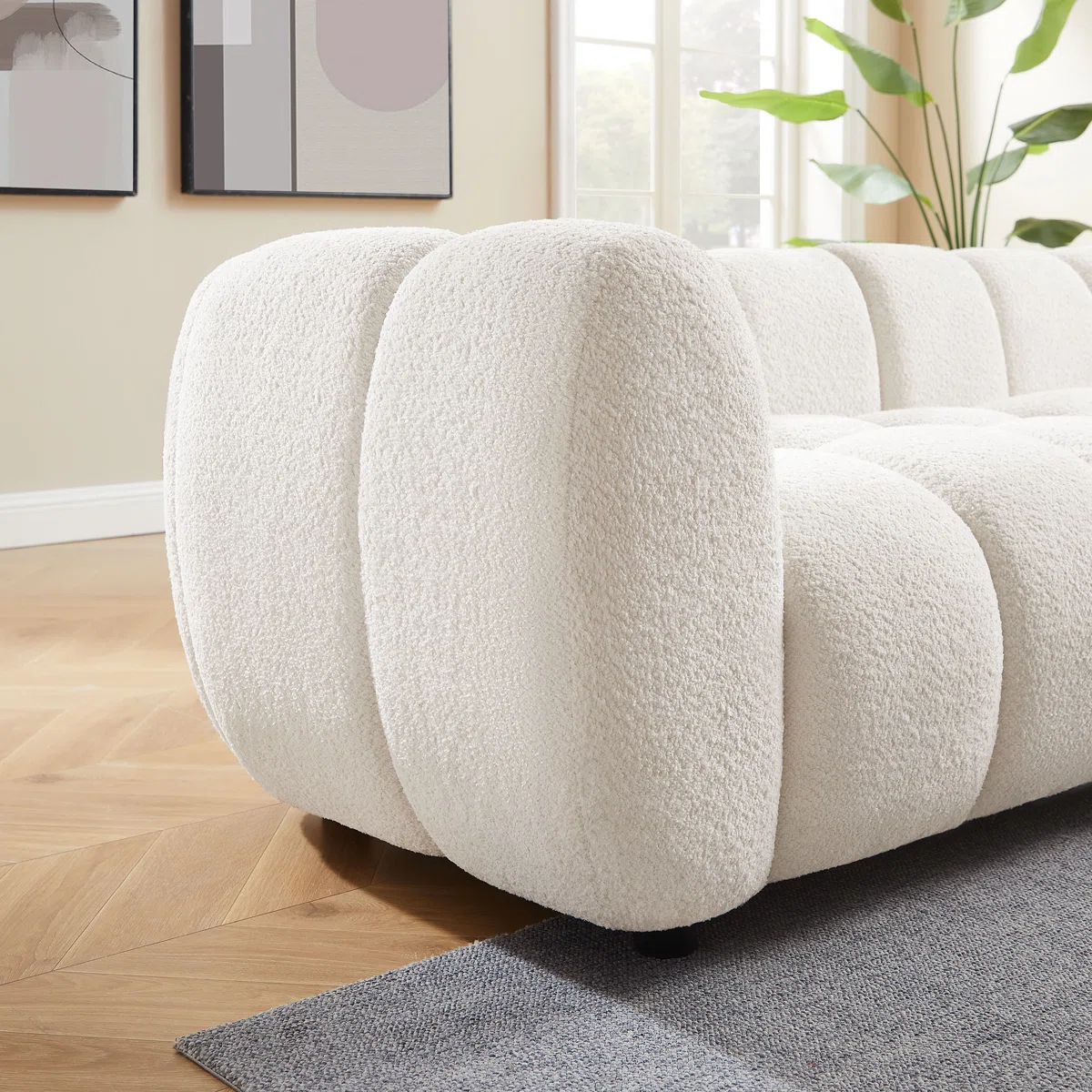 White tufted boucle sofa with rolled arms and throw pillows in a modern living room setting.