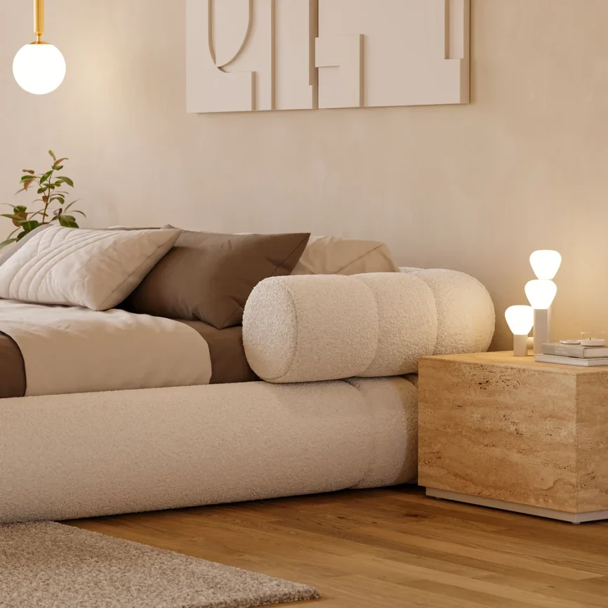 A plush queen-size floor bed upholstered in textured white boucle fabric, featuring a rounded frame and a sculptural headboard