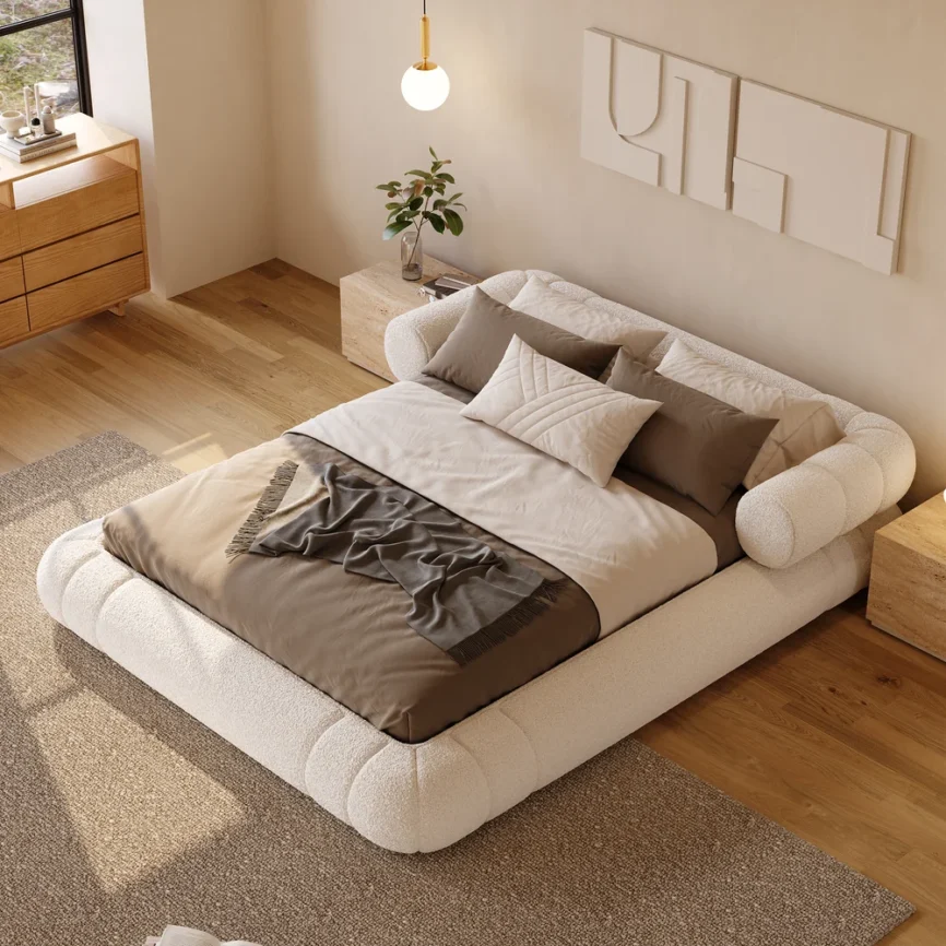 A plush queen-size floor bed upholstered in textured white boucle fabric, featuring a rounded frame and a sculptural headboard