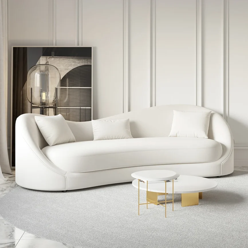 White curved 3-seater sofa with throw pillows and gold coffee table in a modern minimalist living room