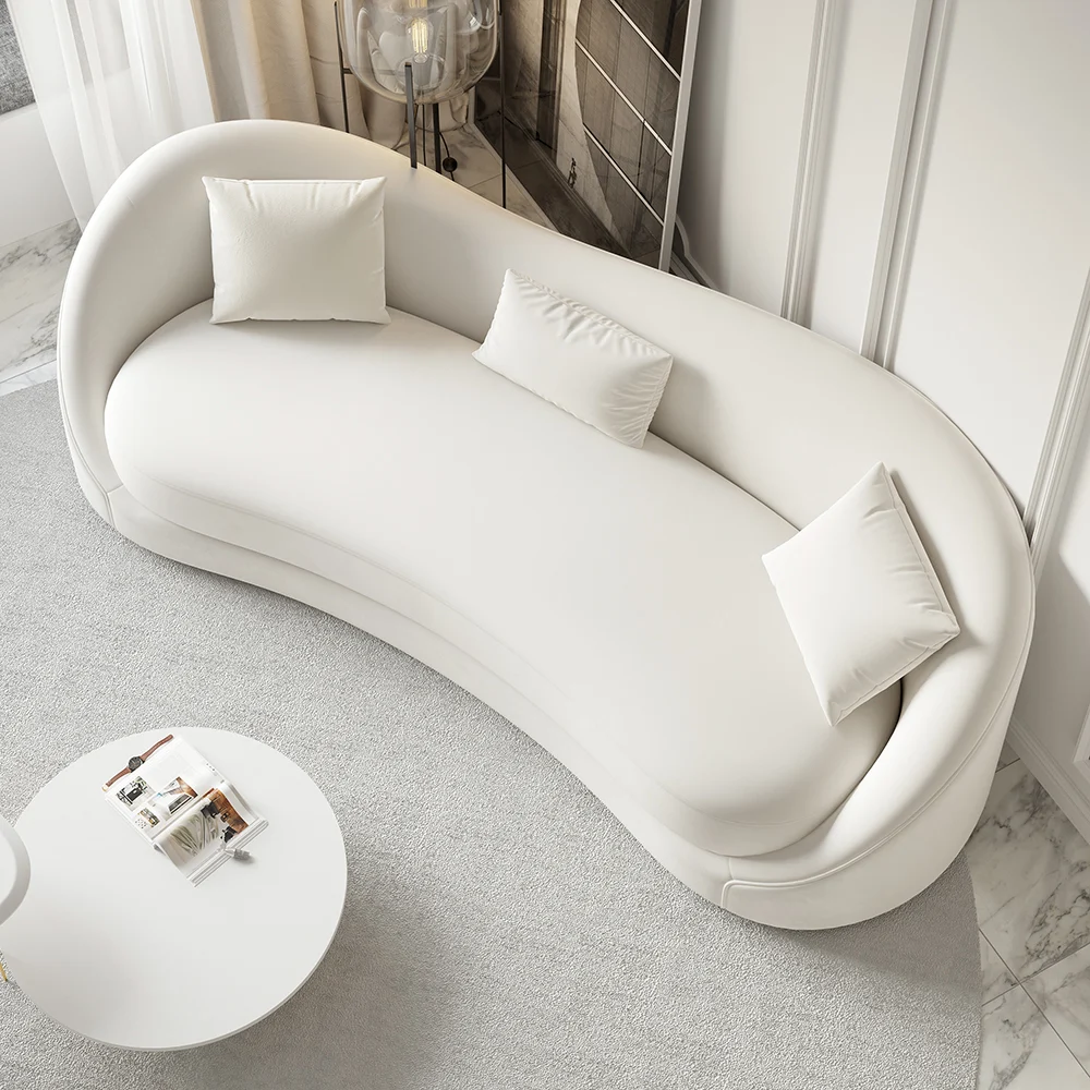 White curved 3-seater sofa with throw pillows and gold coffee table in a modern minimalist living room