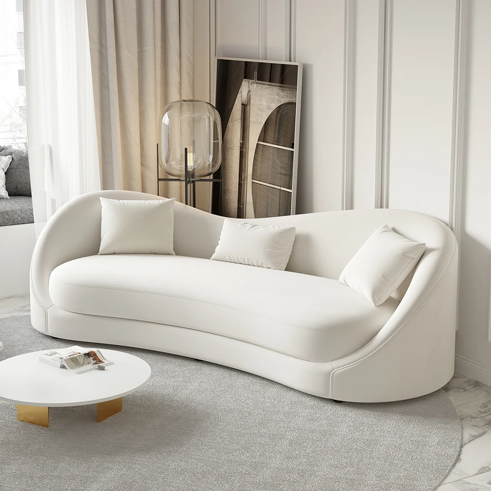 White curved 3-seater sofa with throw pillows and gold coffee table in a modern minimalist living room