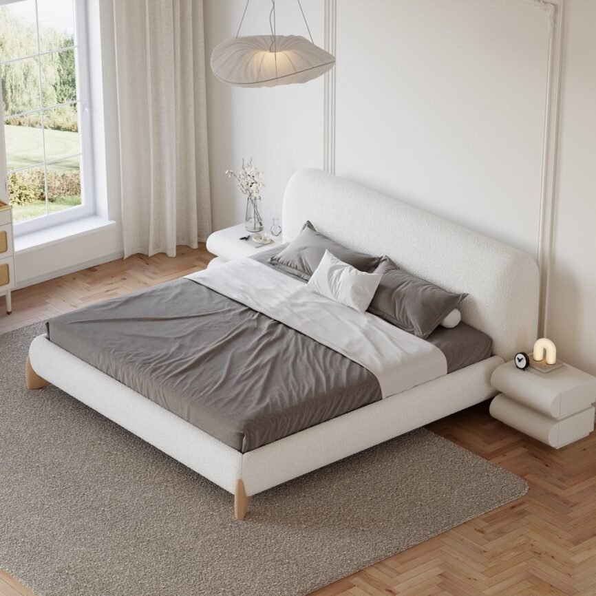 White boucle upholstered bed with padded headboard, gray bedding, and white nightstands in a minimalist bedroom.