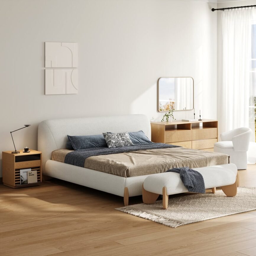 White boucle upholstered bed with padded headboard, gray bedding, and white nightstands in a minimalist bedroom.