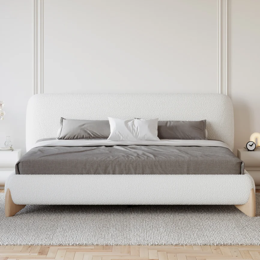White boucle upholstered bed with padded headboard, gray bedding, and white nightstands in a minimalist bedroom.