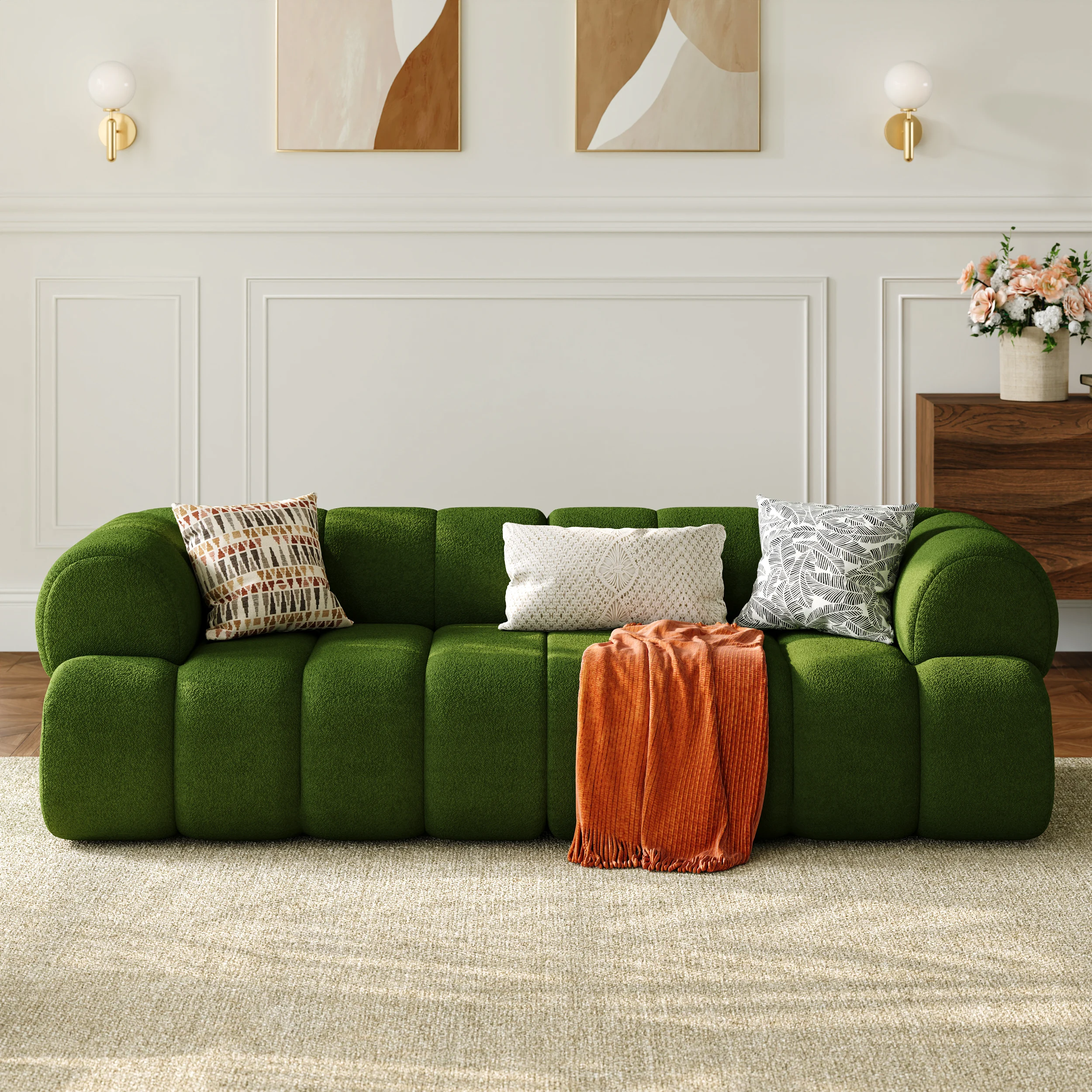 Green block-style sofa with three throw pillows and orange blanket in a contemporary interior