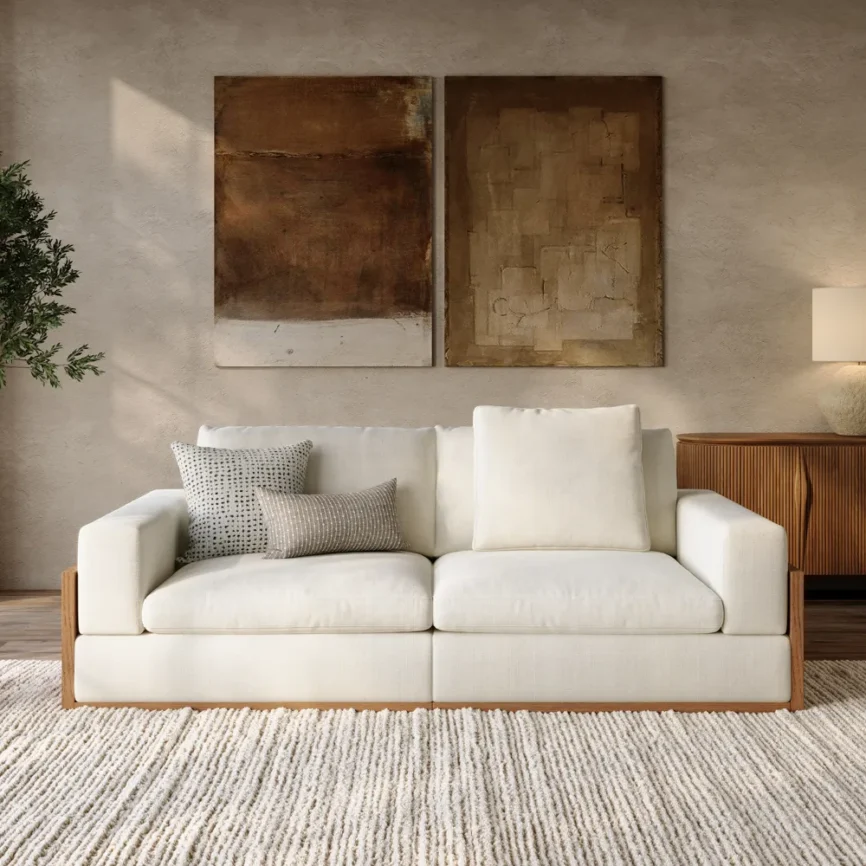Modern white upholstered sofa with wooden base, throw pillows, and textured rug in cozy living room