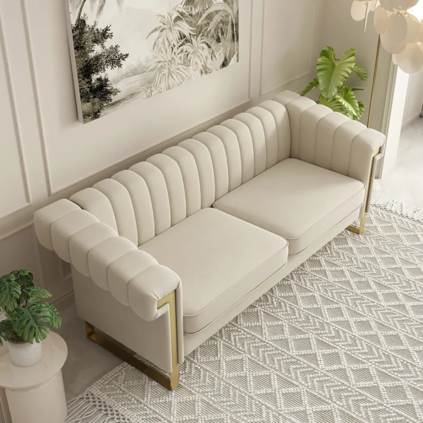 Modern cream velvet 3-seater sofa with vertical channel tufting, square arms, gold metal legs, and two removable seat cushions in a contemporary living room. Description: