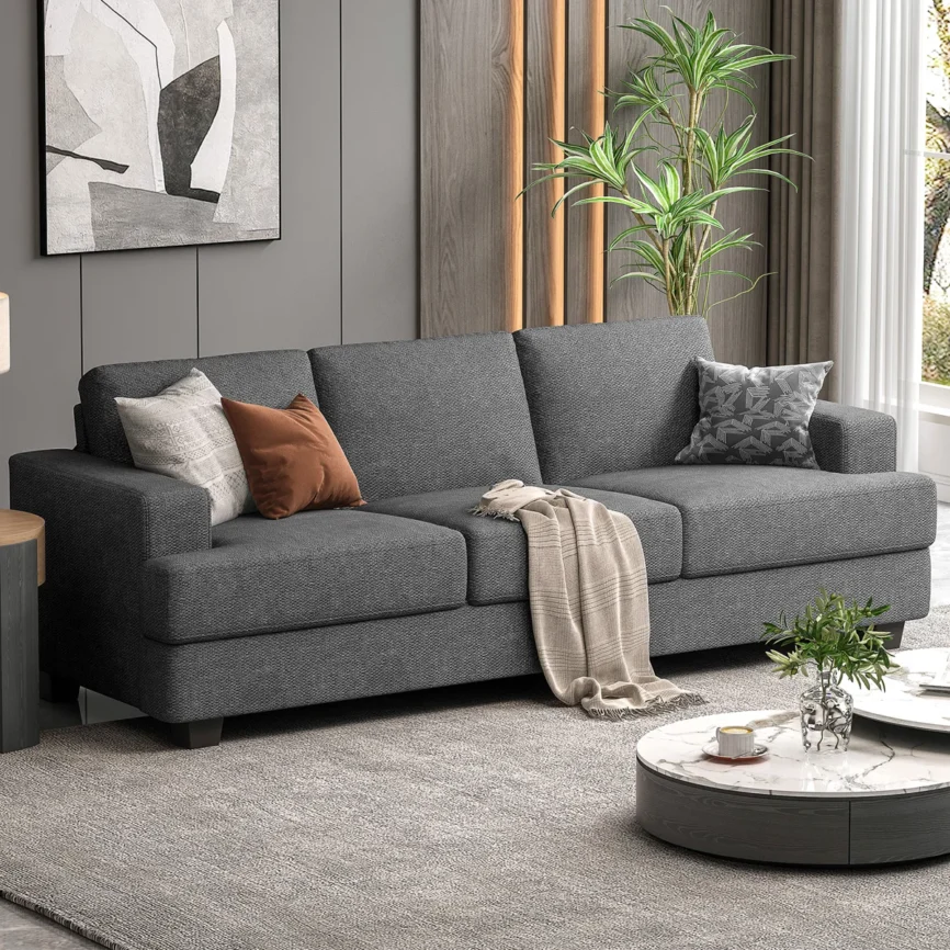 Gray three-seat sofa with textured fabric, accent pillows, and throw blanket in a stylish living room.