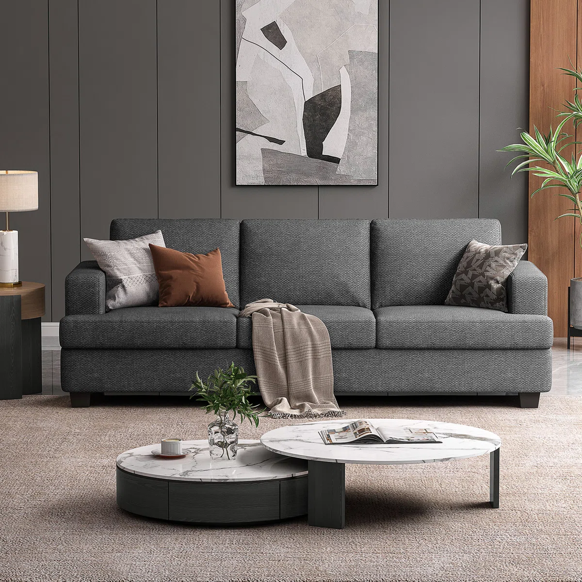 Gray three-seat sofa with textured fabric, accent pillows, and throw blanket in a stylish living room.