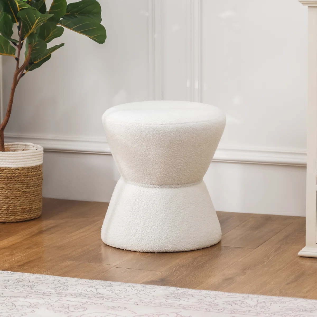 white hourglass-shaped ottoman with soft textured fabric in minimalist interior setting