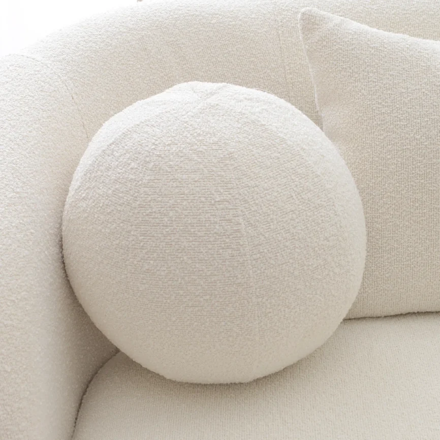 A light beige upholstered sofa with a rounded back and arms, styled in a minimalist living room.