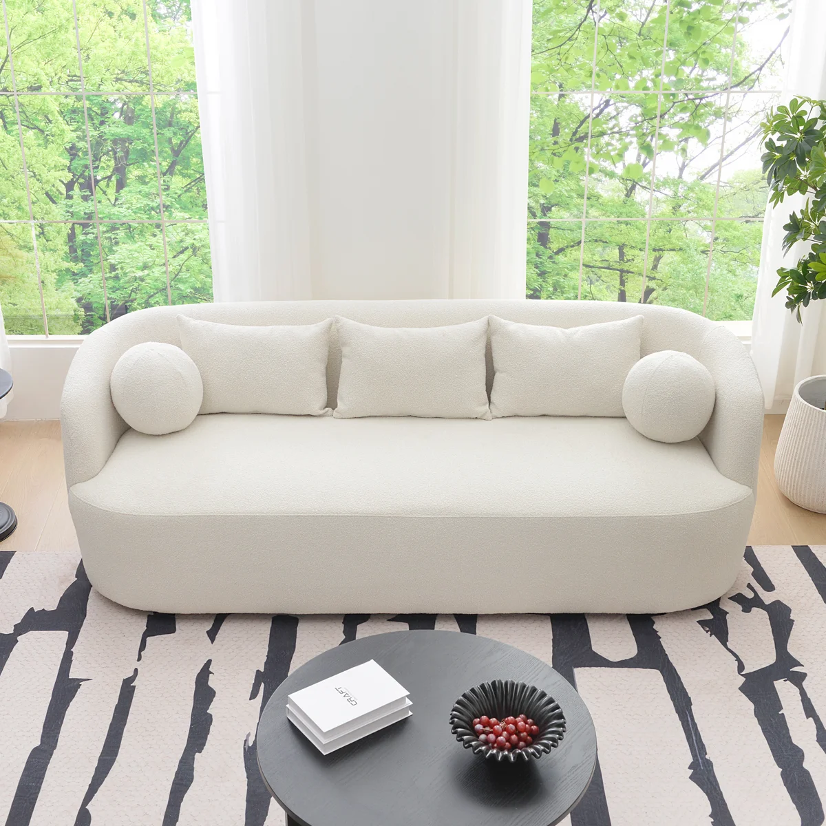 A light beige upholstered sofa with a rounded back and arms, styled in a minimalist living room.