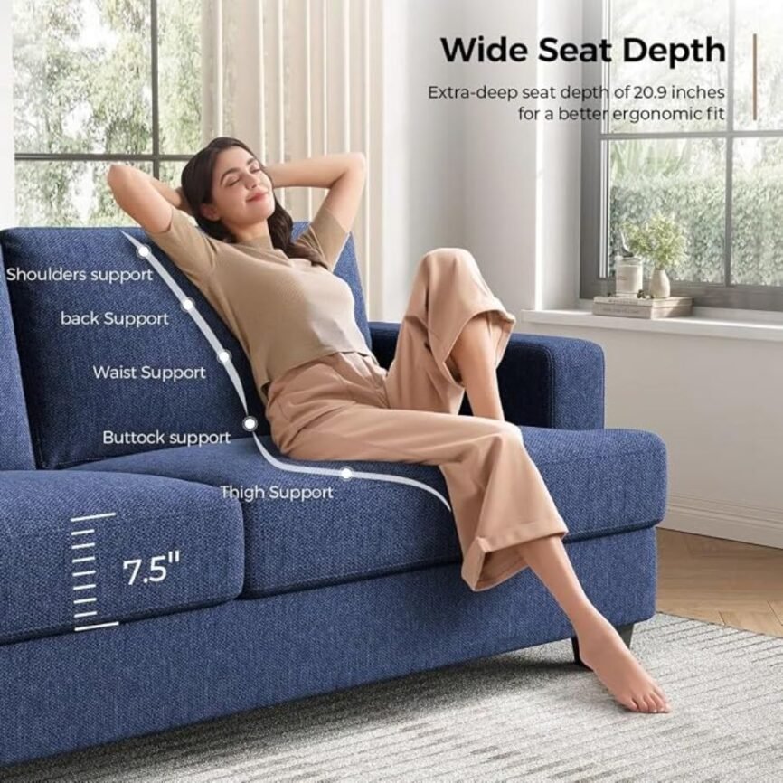 Blue upholstered sofa with houndstooth and beige pillows, throw blanket, and natural light in modern living room