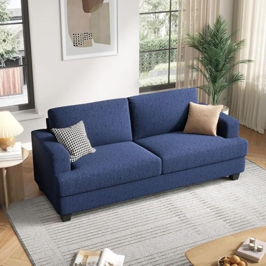 Blue upholstered sofa with houndstooth and beige pillows, throw blanket, and natural light in modern living room