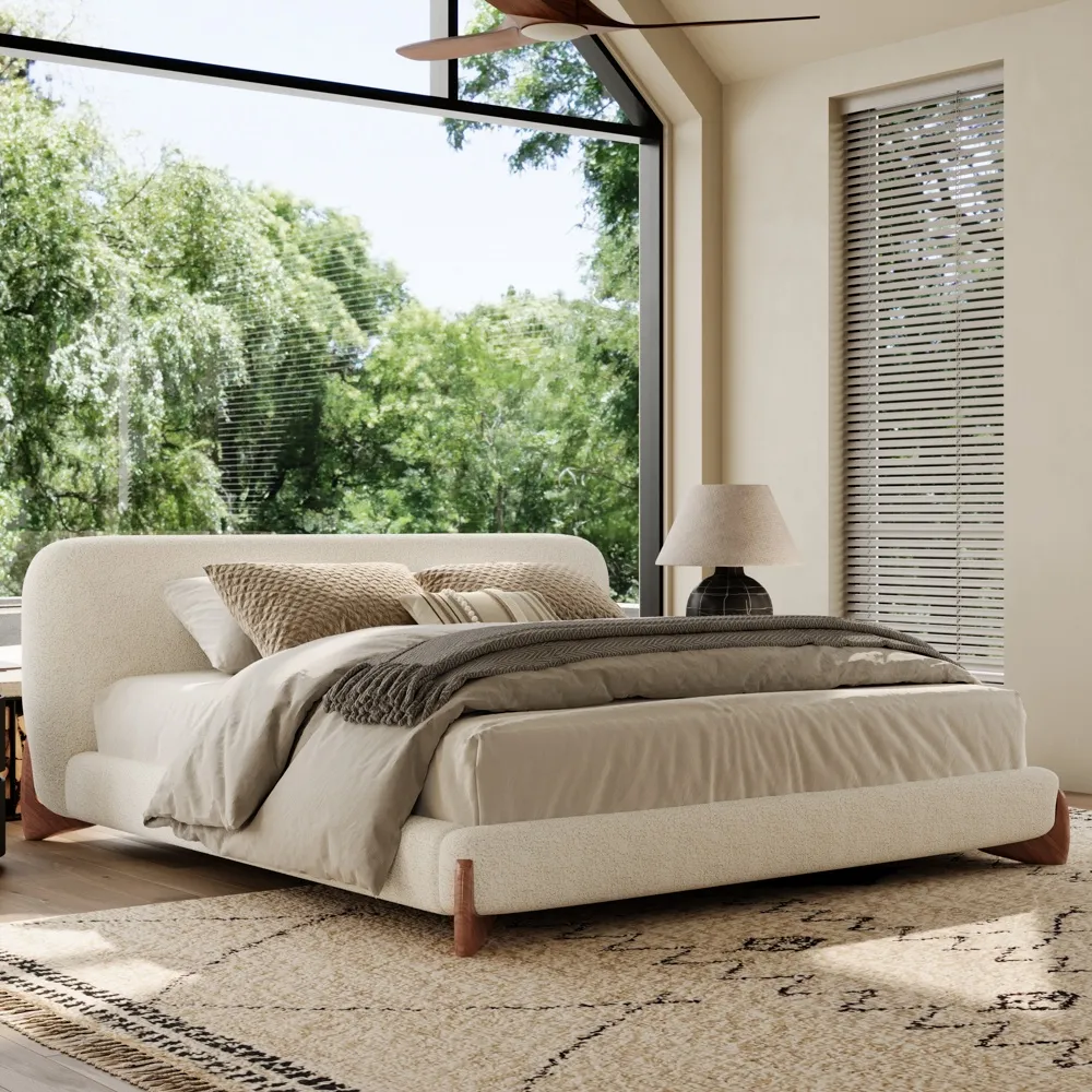 A minimalist upholstered bed in textured white boucle fabric with rounded edges and outward-curving wooden legs.