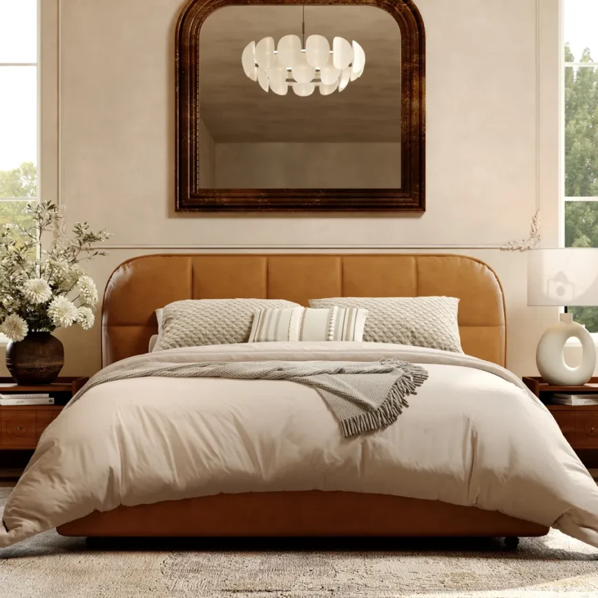 Toast Leather Bed in brown with beige bedding, decorative pillows, and wooden nightstands in a cozy bedroom setting.