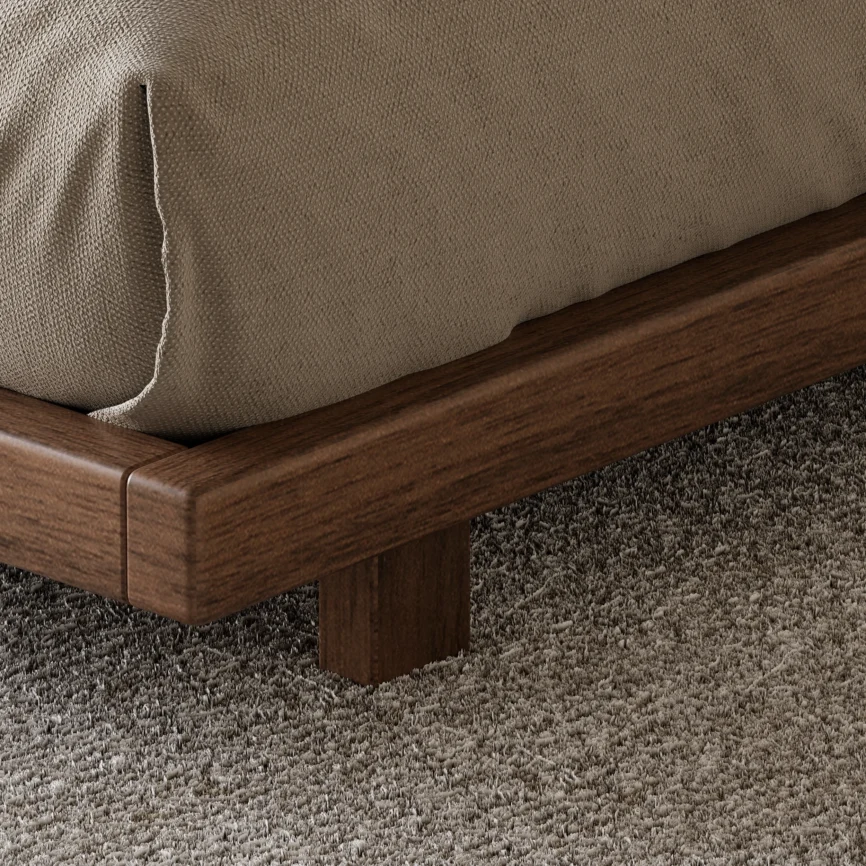 A minimalist king-size floor bed with a walnut wood finish and low-profile frame, styled with beige bedding and a textured gray throw blanket