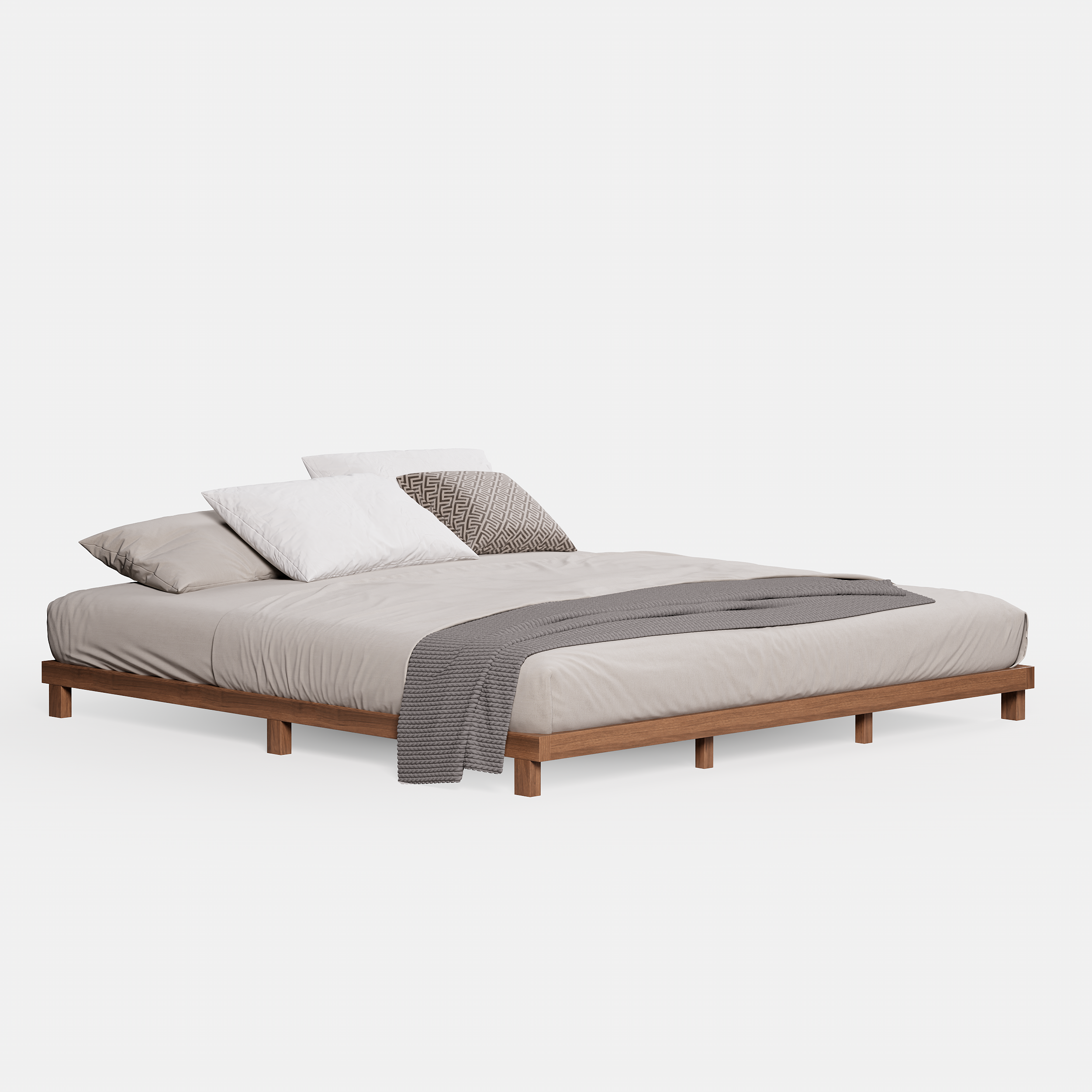 A minimalist king-size floor bed with a walnut wood finish and low-profile frame, styled with beige bedding and a textured gray throw blanket