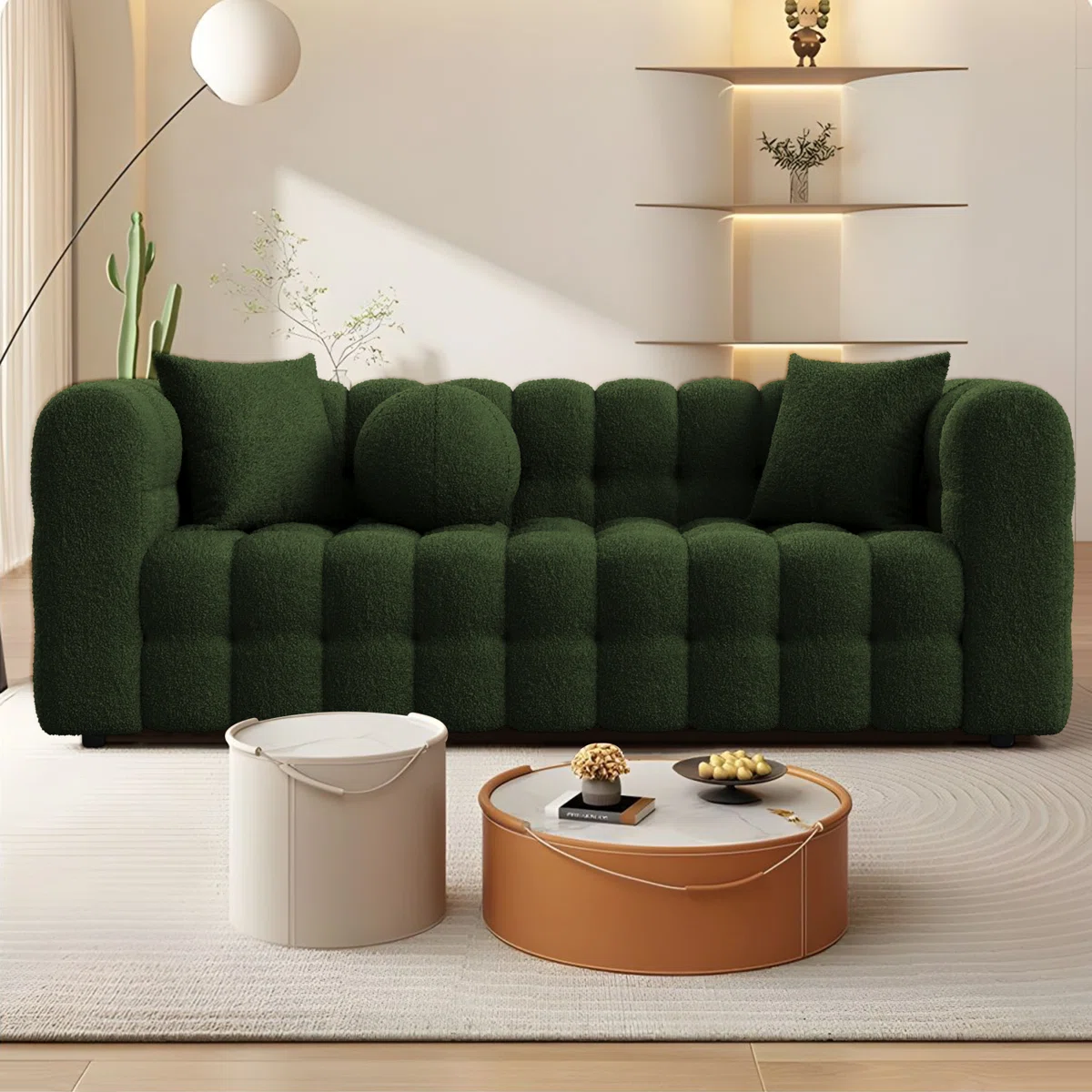 Dark green tufted sofa with three accent pillows in a minimalist living room with wood flooring and natural light