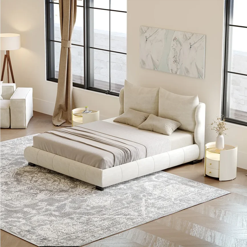 A modern upholstered queen bed in soft beige fabric with a rounded, cushioned frame and short black legs