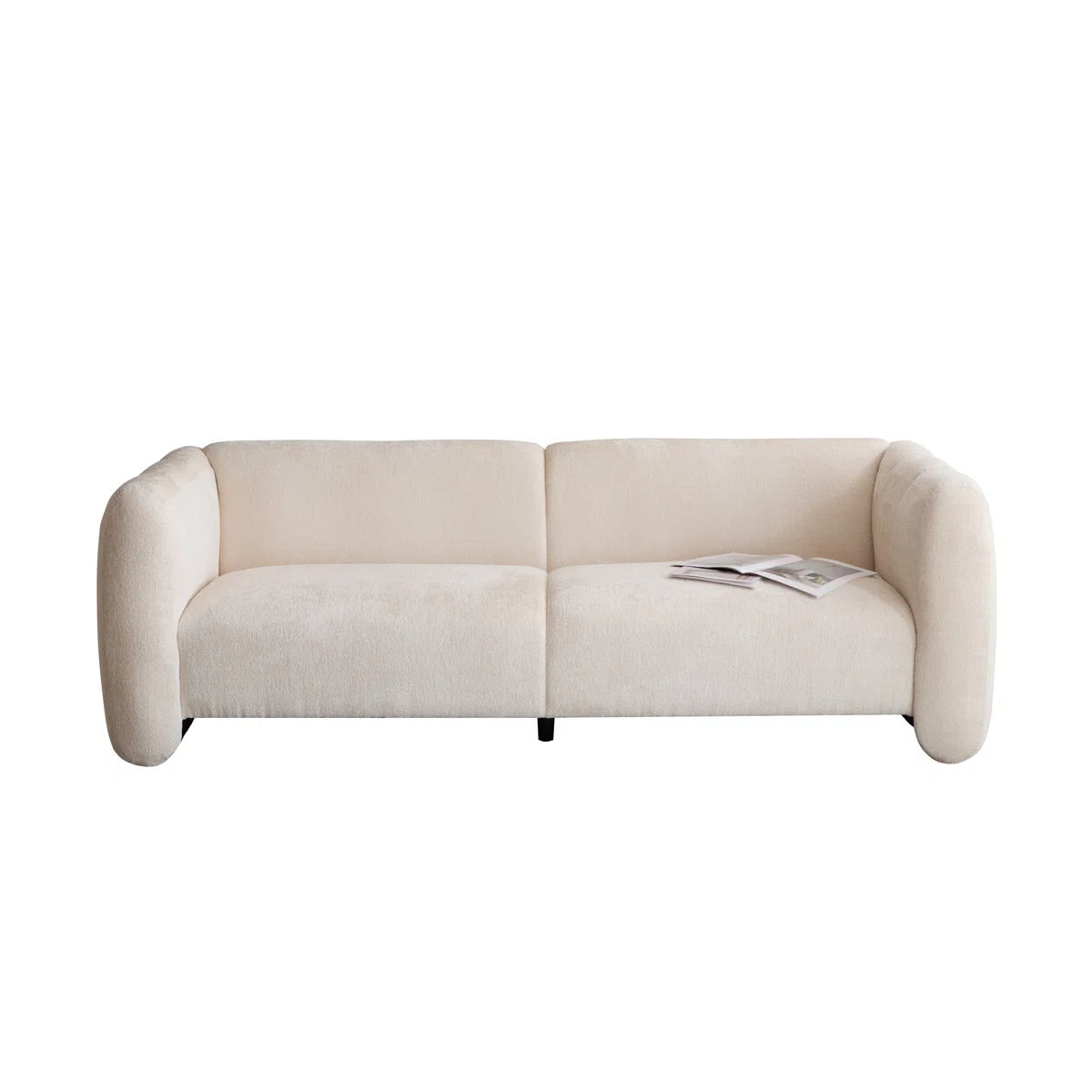 Modern beige boucle sofa with plush cushions, black legs, and throw pillows in a minimalist room.