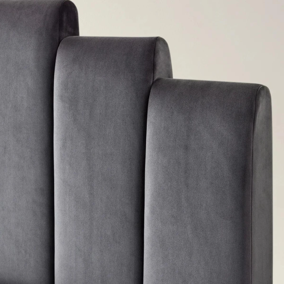 Gunmetal velvet bed with geometric tufted headboard and footboard, styled with white bedding in a modern room.