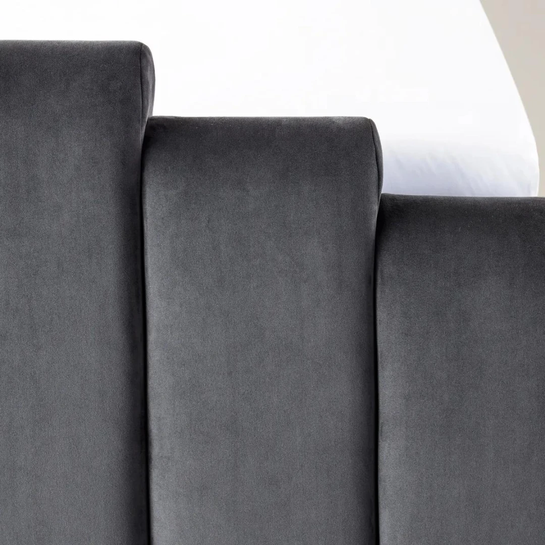 Gunmetal velvet bed with geometric tufted headboard and footboard, styled with white bedding in a modern room.