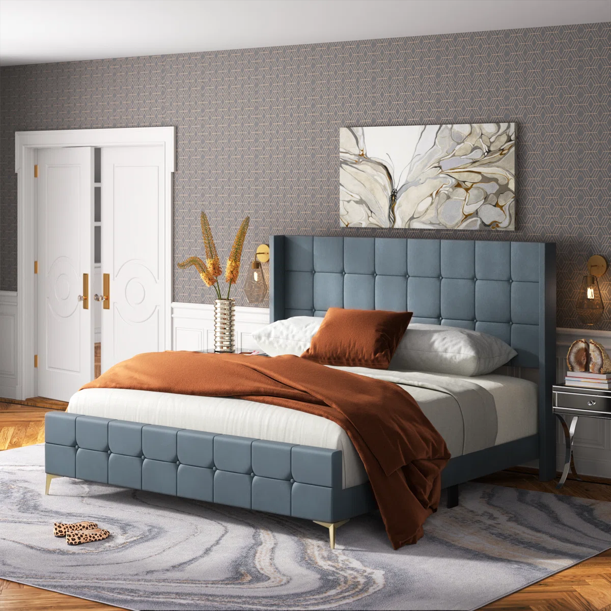 Muted blue velvet bed with grid-tufted headboard and footboard, gray bedding, and gold legs in a modern bedroom.