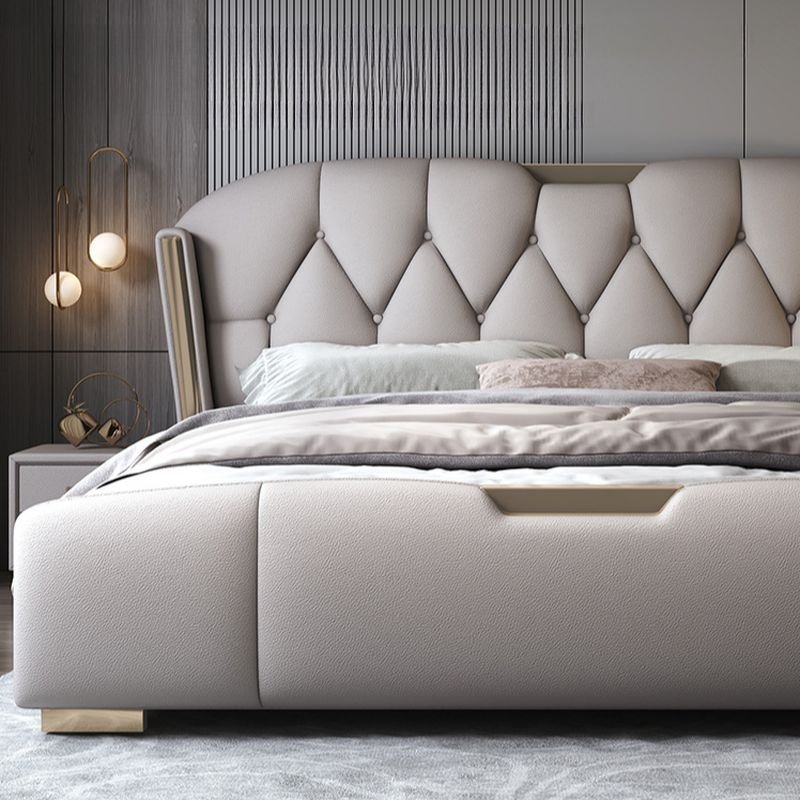 Tufted wingback bed with diamond-pattern headboard, neutral bedding, and modern wall-mounted lights.