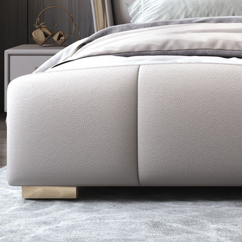 Tufted wingback bed with diamond-pattern headboard, neutral bedding, and modern wall-mounted lights.