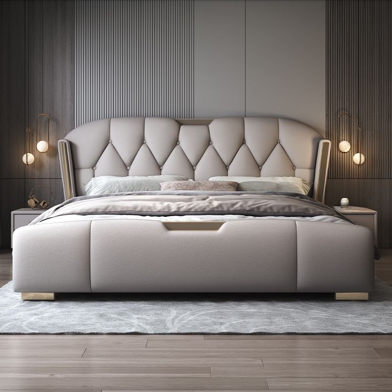 Tufted wingback bed with diamond-pattern headboard, neutral bedding, and modern wall-mounted lights.