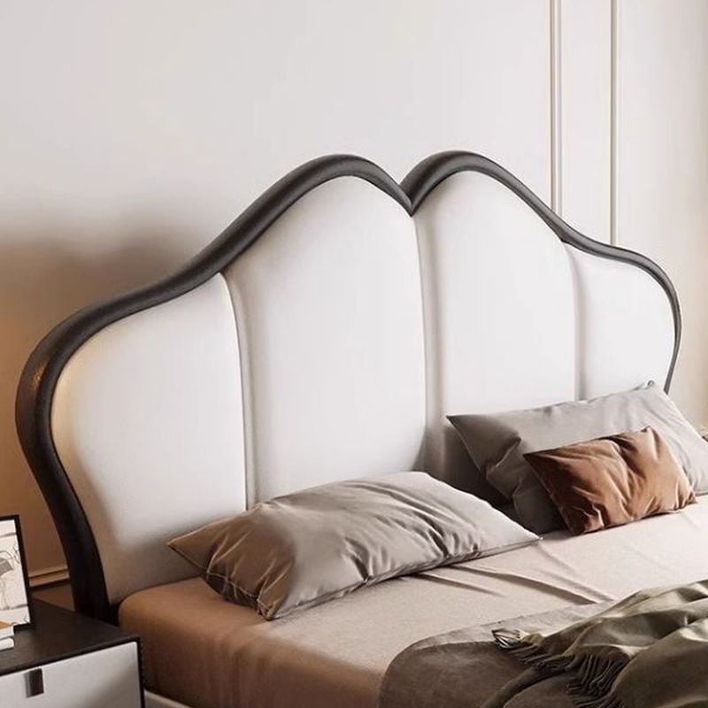 A modern bedroom featuring a white upholstered bed with a curved panel headboard outlined in black