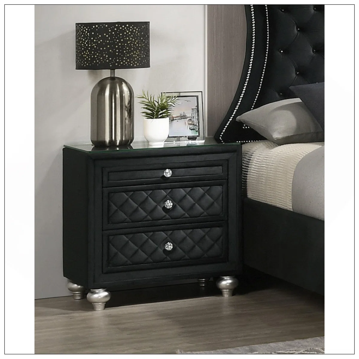 A glamorous black velvet nightstand featuring three tufted drawers with faux crystal knobs and a sleek 8mm tempered glass top