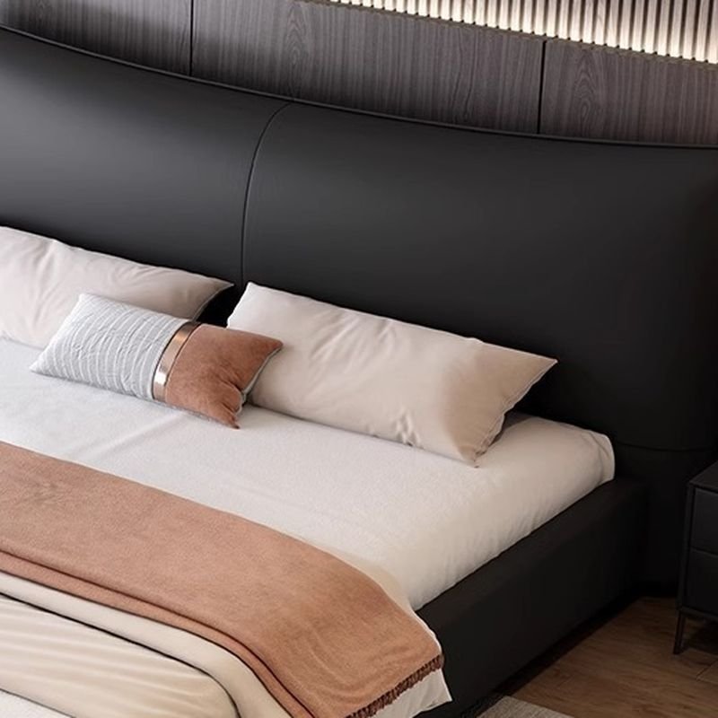 Black curved headboard bed with neutral bedding, modern nightstands, and dark wood-paneled wall.