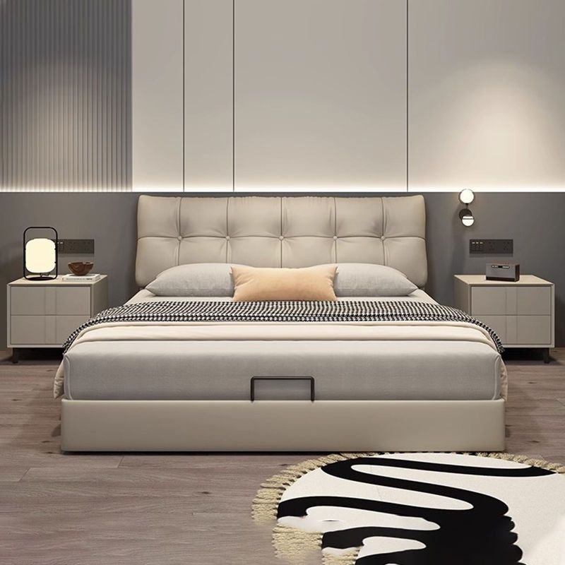 Cream tufted bed with storage handle, patterned blanket, and modern nightstands with built-in lighting.