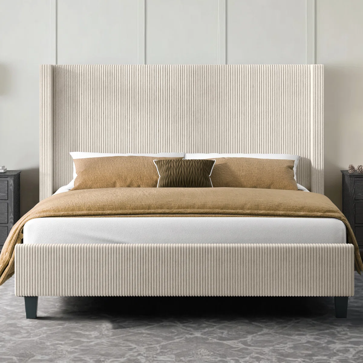 Beige upholstered bed with ribbed headboard, layered pillows, tan comforter, and dark nightstand in a modern bedroom.