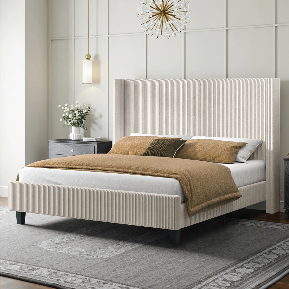 Beige upholstered bed with ribbed headboard, layered pillows, tan comforter, and dark nightstand in a modern bedroom.