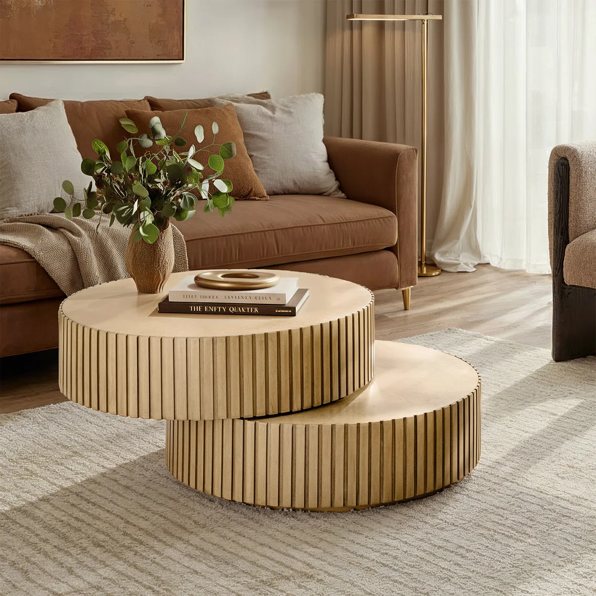 Round swivel‑top coffee table with dual rotating surfaces, fluted base, and natural birch veneer finish, styled as a modern centerpiece in a living room.